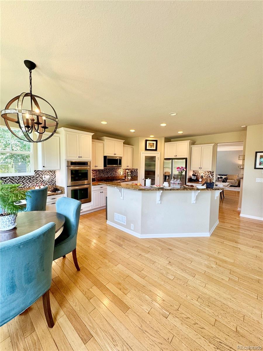 2896 Gemini Loop Broomfield, CO 80023 - Photo 16 of 49 a large kitchen with stainless steel appliances granite countertop a living room and couches with wooden floor