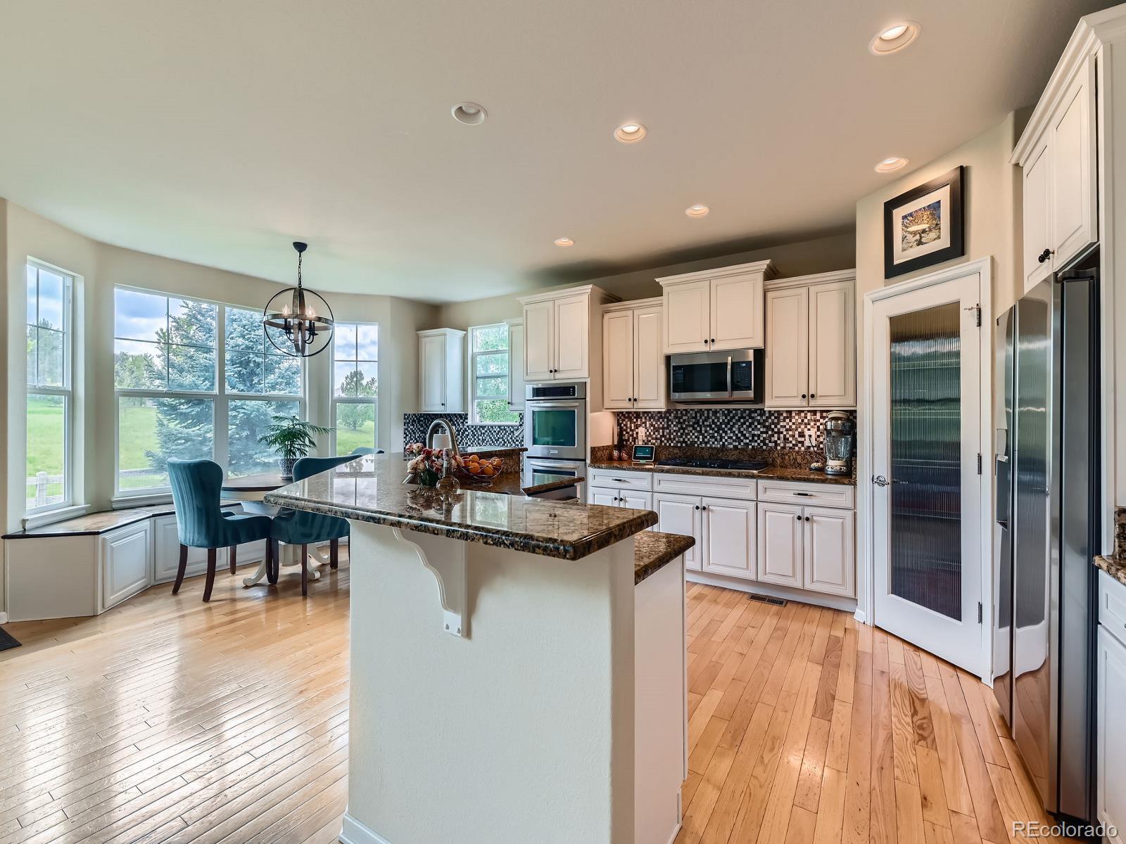 2896 Gemini Loop Broomfield, CO 80023 - Photo 17 of 49 a kitchen with stainless steel appliances granite countertop a stove top oven a sink dishwasher a dining table and chairs with wooden floor