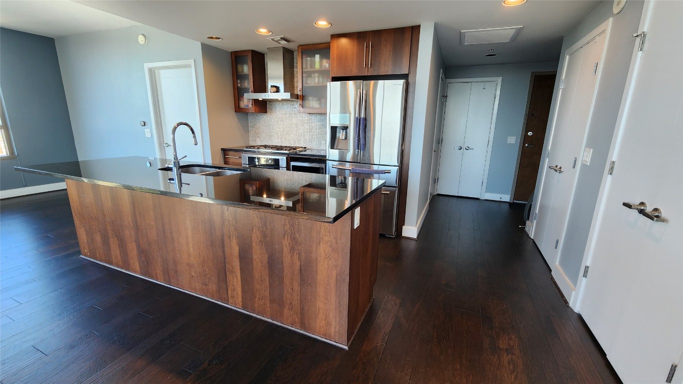300 Bowie Street, Unit 1305 Austin, TX 78703 - Photo 6 of 38 a kitchen with stainless steel appliances a refrigerator a sink dishwasher a oven a wooden cabinets and floor