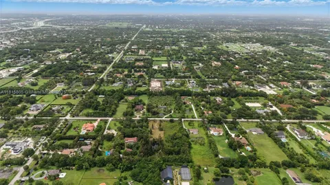 an aerial view of residential houses with outdoor space and trees
