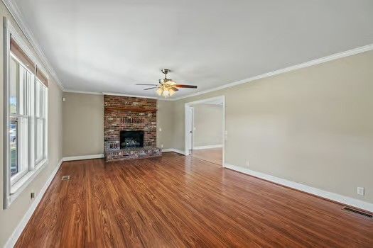 an empty room with wooden floor fireplace and windows