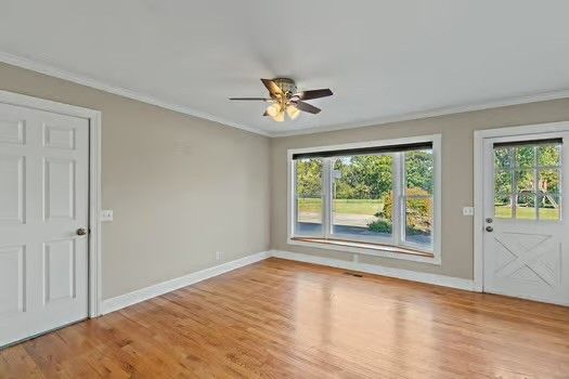 a view of empty room with wooden floor and fan