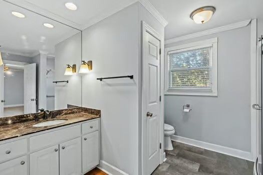 a bathroom with a granite countertop sink mirror vanity and toilet