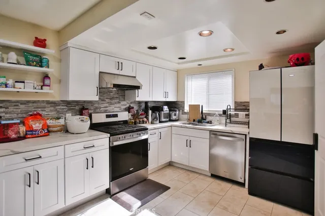 a kitchen with stainless steel appliances granite countertop a refrigerator and a stove top oven