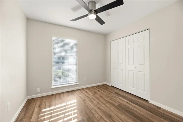 a view of empty room with wooden floor and fan