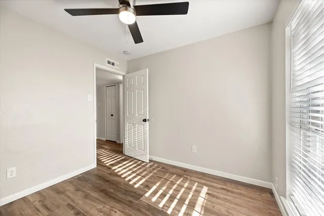 a view of empty room with wooden floor and fan
