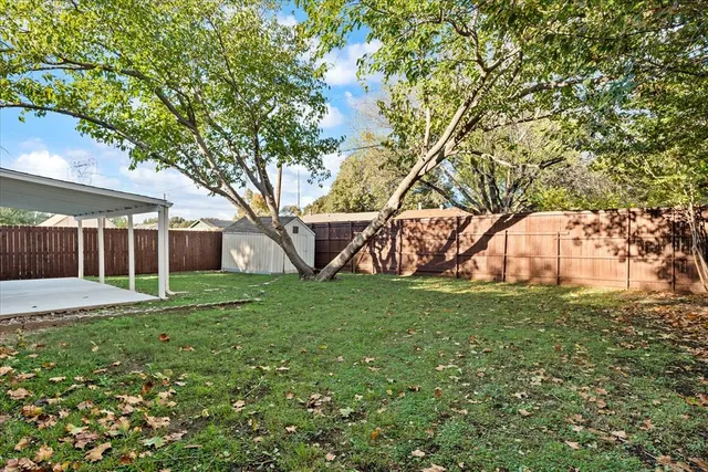 a view of a yard in front of a house with large trees