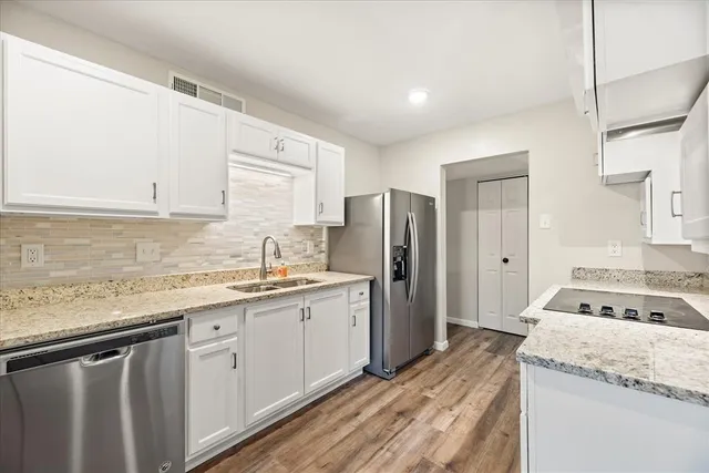 a kitchen with granite countertop kitchen island stainless steel appliances a refrigerator sink and cabinets