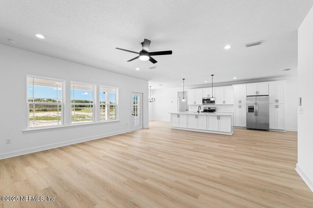 14299 Saddle Ridge Road Macclenny, FL 32063 - Photo 3 of 35 a view of open kitchen with white cabinets and wooden floor