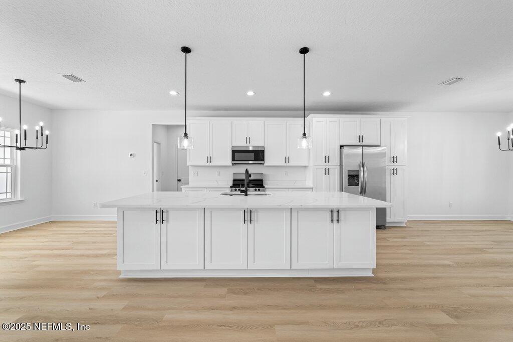 14299 Saddle Ridge Road Macclenny, FL 32063 - Photo 4 of 35 a view of kitchen with stainless steel appliances granite countertop a stove a sink refrigerator and white cabinets with wooden floor