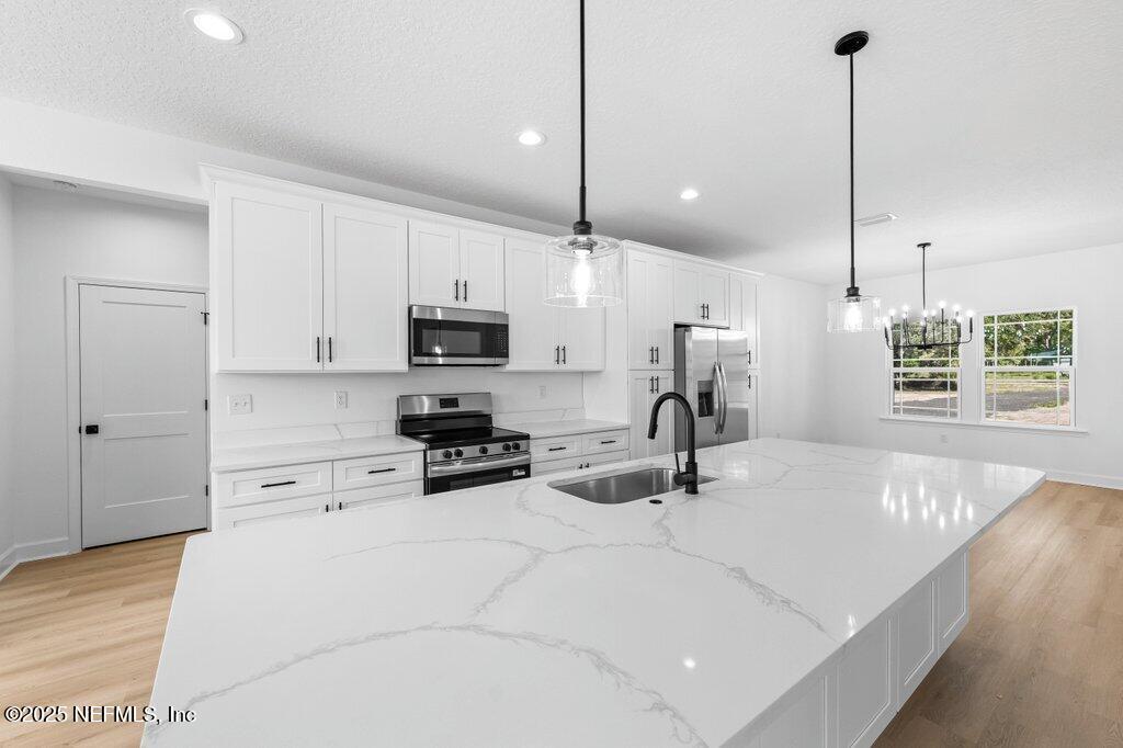 14299 Saddle Ridge Road Macclenny, FL 32063 - Photo 6 of 35 a kitchen with stainless steel appliances kitchen island granite countertop a sink a stove and a wooden floors