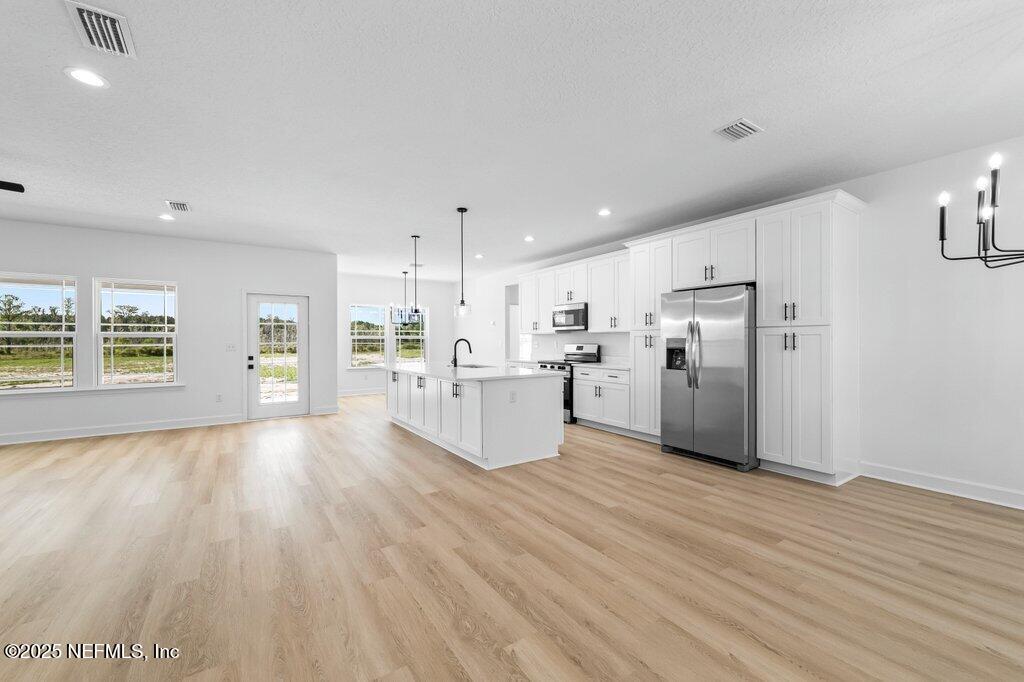 14299 Saddle Ridge Road Macclenny, FL 32063 - Photo 8 of 35 a large kitchen with stainless steel appliances kitchen island a large counter top and a refrigerator