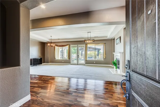 an empty room with chandelier fan and windows