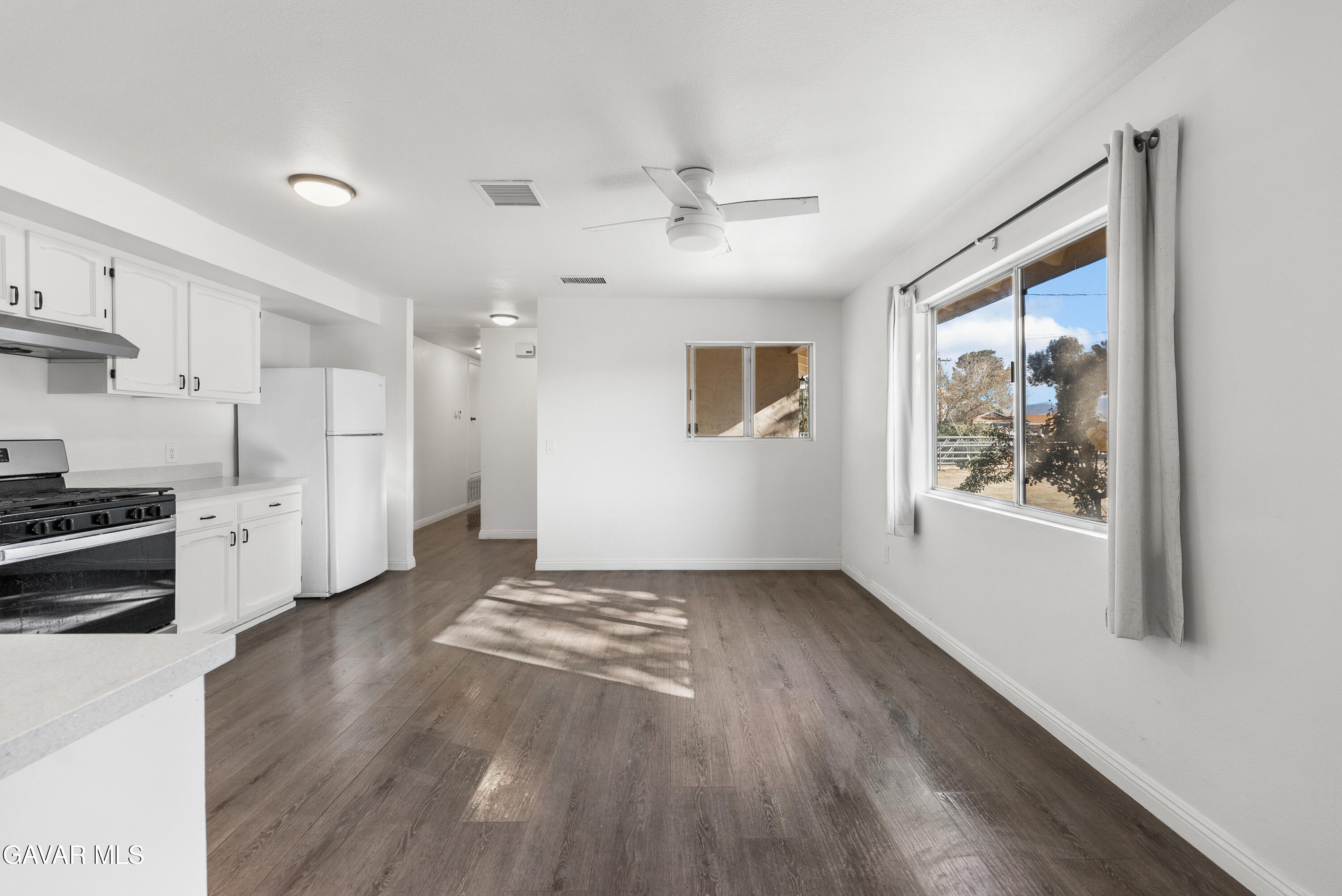 9459 East Ave T 2 Littlerock, CA 93543 - Photo 16 of 54 a living room with stainless steel appliances kitchen island granite countertop a stove a refrigerator a sink a dining table and chairs with wooden floor