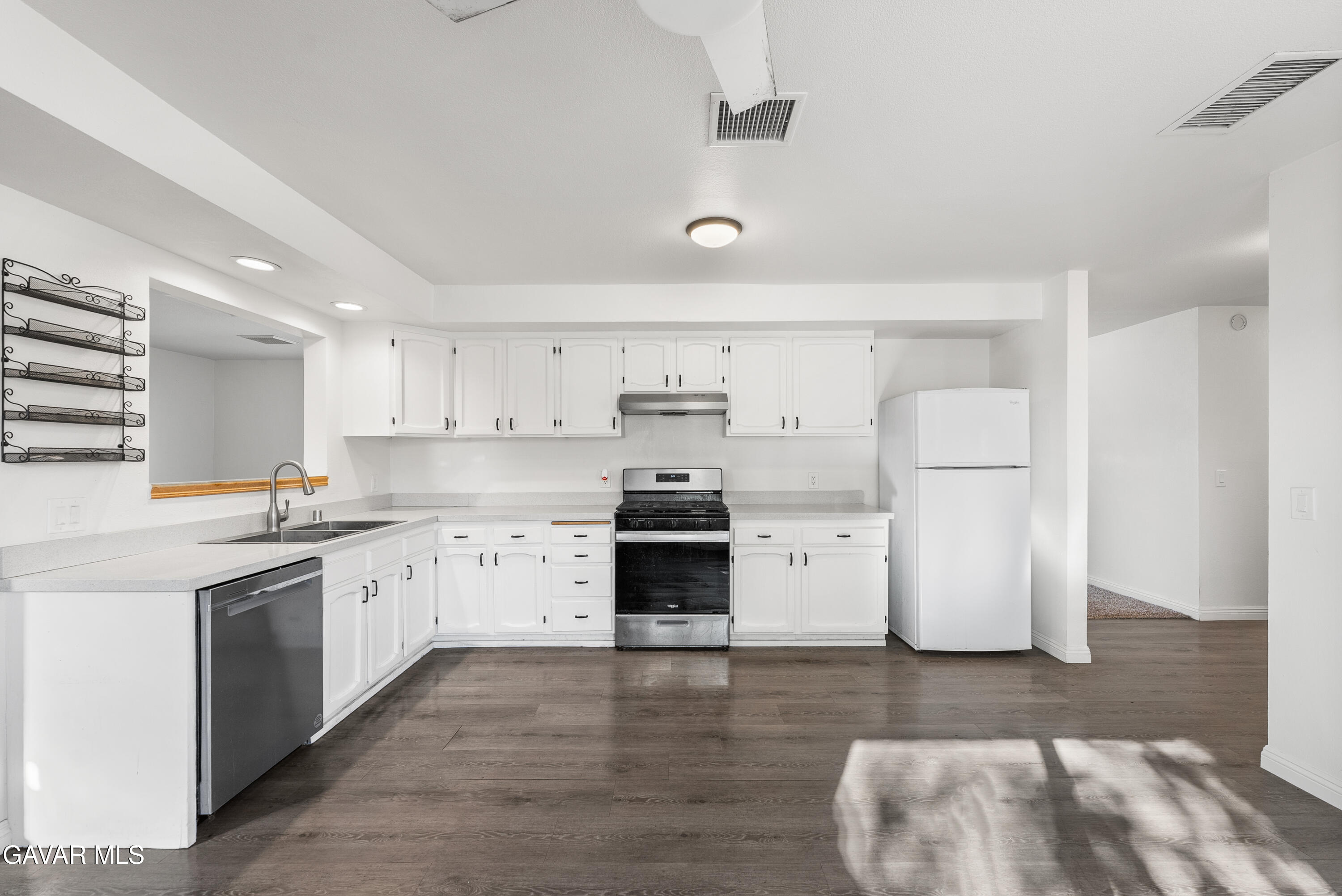 9459 East Ave T 2 Littlerock, CA 93543 - Photo 18 of 54 a kitchen with stainless steel appliances a stove a refrigerator and white cabinets