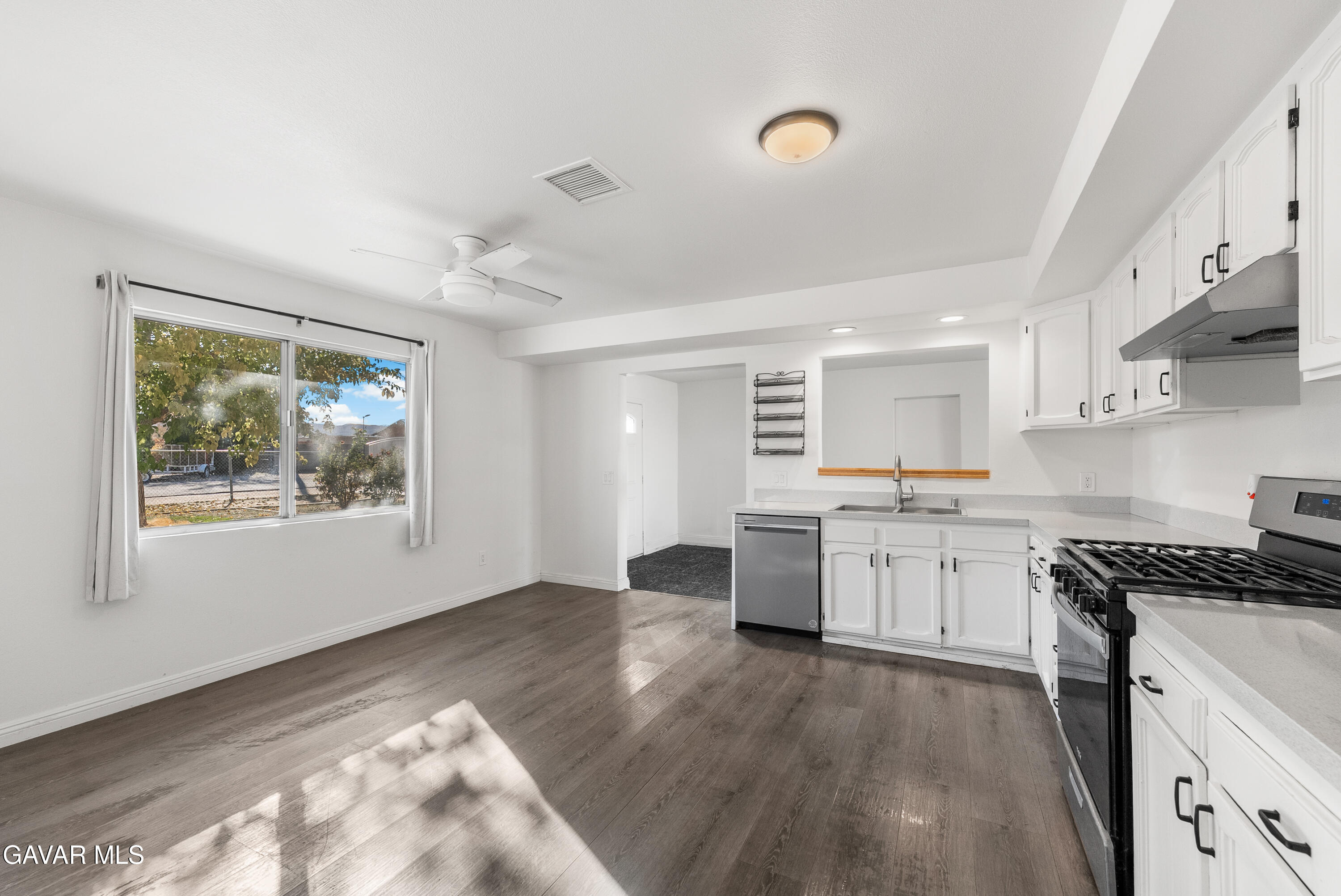 9459 East Ave T 2 Littlerock, CA 93543 - Photo 22 of 54 a kitchen with granite countertop a stove a sink a refrigerator and white cabinets with wooden floor
