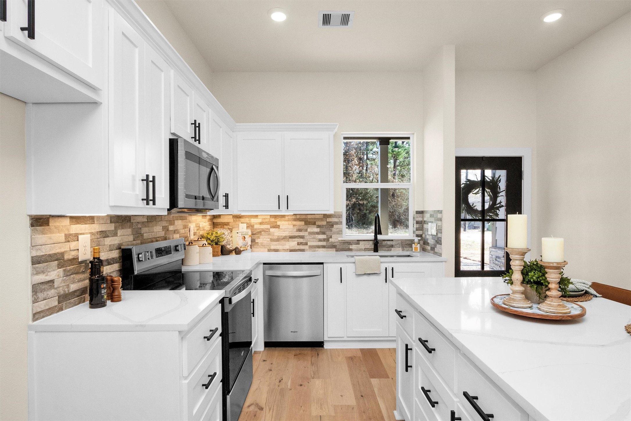 103 Canary St Point Point Blank, TX 77364 - Photo 6 of 28 a kitchen with a sink dishwasher stove and white cabinets