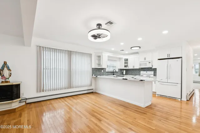 a view of kitchen with stainless steel appliances granite countertop a stove top oven a sink dishwasher and white cabinets with wooden floor