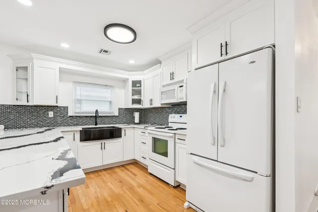 a kitchen with white cabinets and white appliances