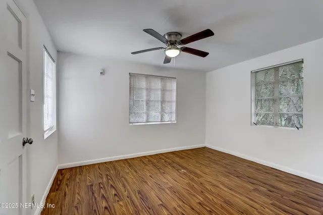 a view of empty room with wooden floor and fan