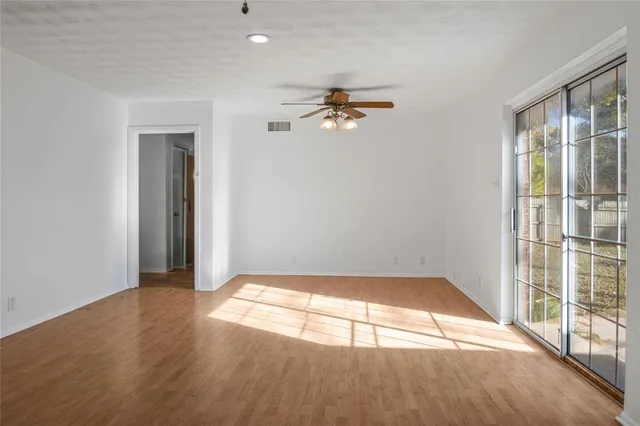 a view of empty room with wooden floor and fan