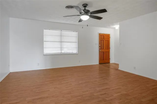 an empty room with a window and a fan