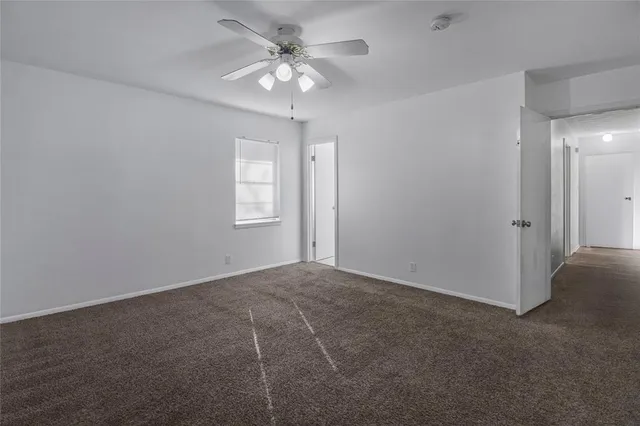 an empty room with chandelier fan and windows