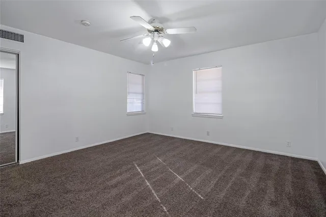 an empty room with windows and chandelier fan