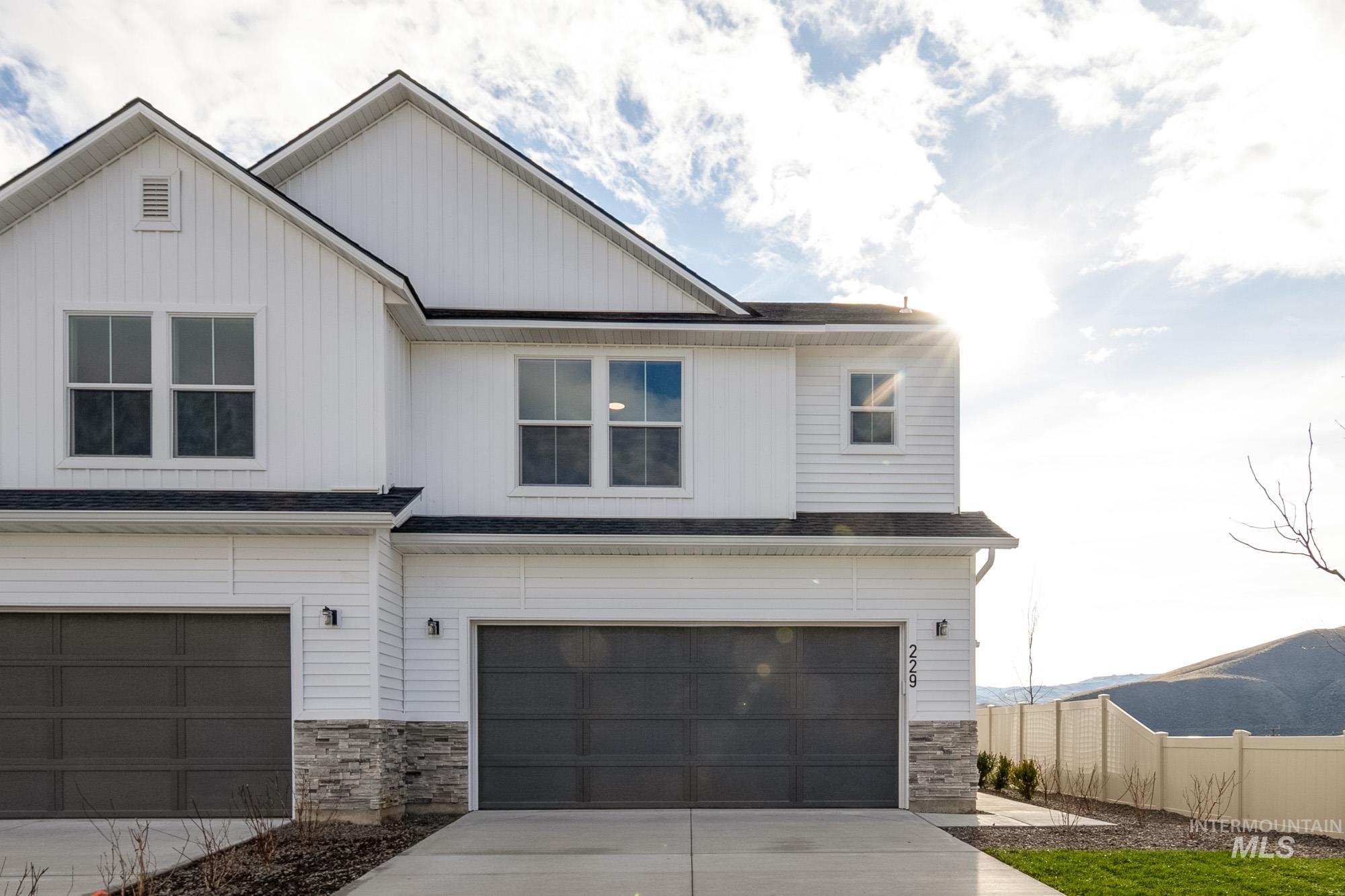 View of front of property featuring concrete driveway, a garage, stone siding, and board and batten siding