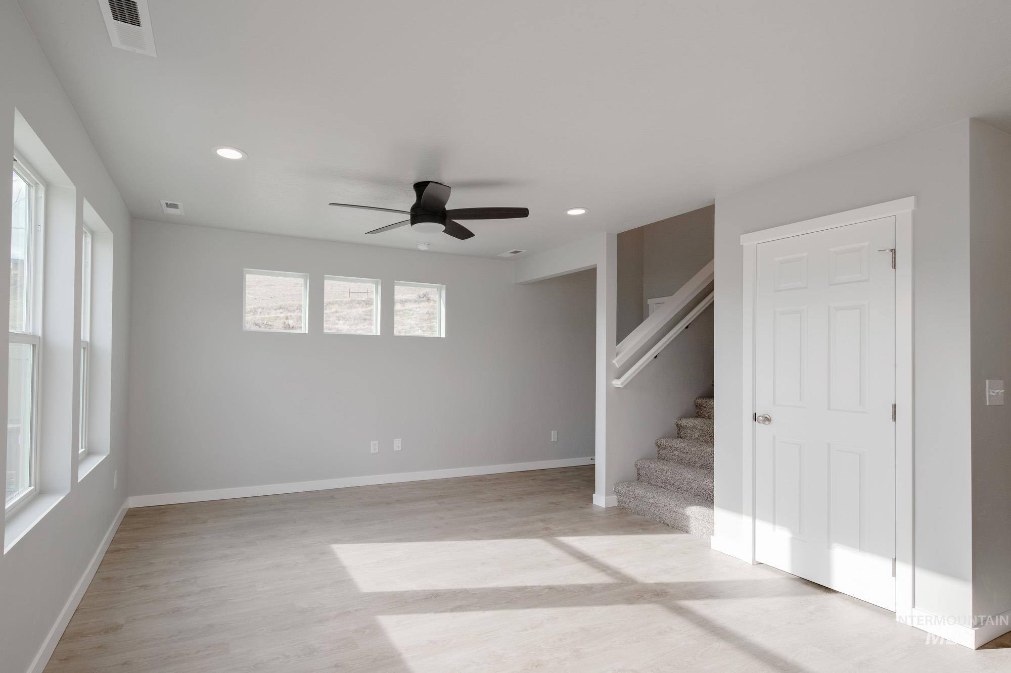 229 Moose Street Horseshoe Bend, ID 83629 - Photo 11 of 26 Unfurnished living room with ceiling fan, recessed lighting, light wood-style floors, and stairway