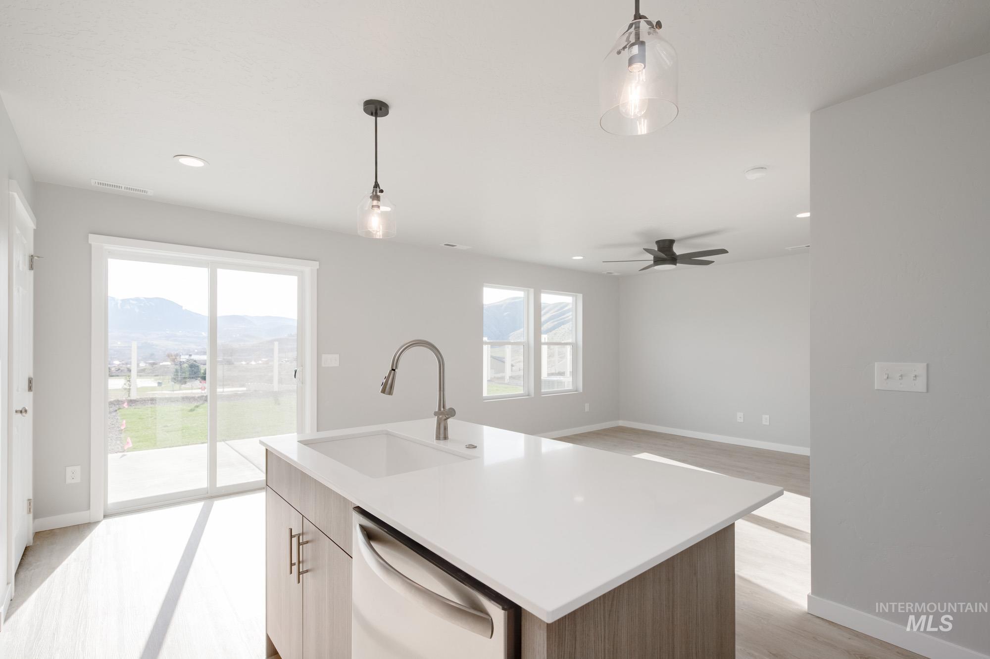 229 Moose Street Horseshoe Bend, ID 83629 - Photo 6 of 26 Kitchen with hanging light fixtures, dishwashing machine, an island with sink, light wood-type flooring, and a mountain view