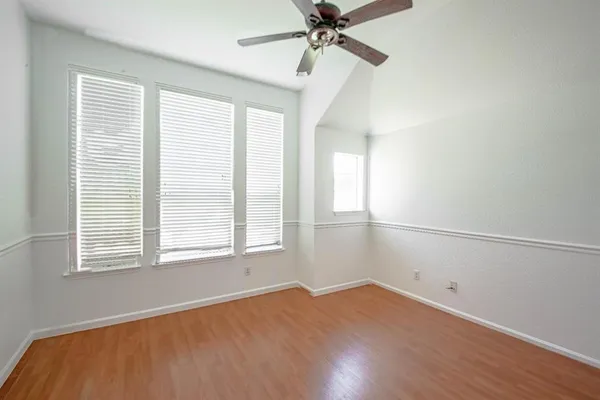 a view of an empty room with a window and wooden floor