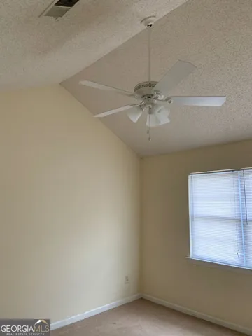 an empty room with a window and a fan