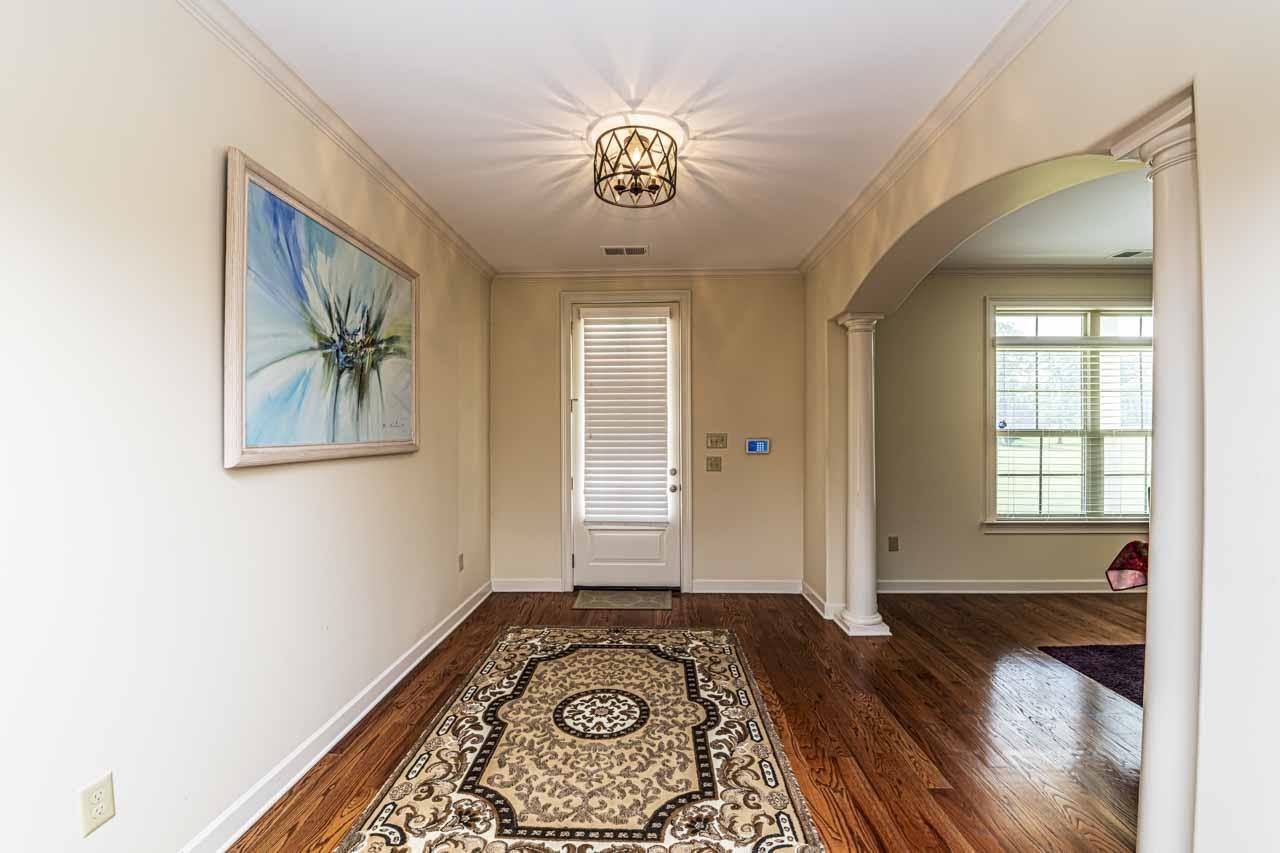 185 Belmont Road Mason, TN 38049 - Photo 22 of 38 Entryway featuring wood-finish flooring, a decorative overhead light fixture, and an arched doorway with structural columns