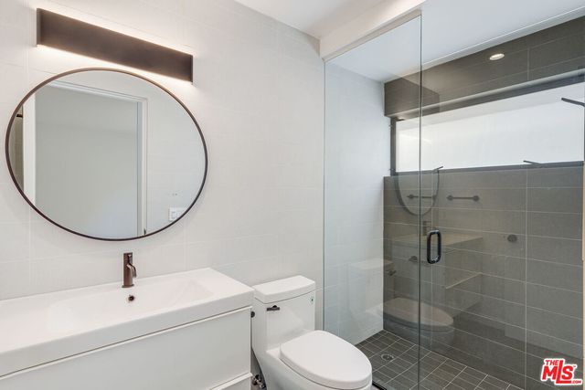 a bathroom with a toilet sink vanity and shower