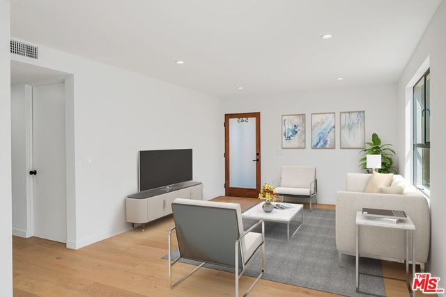 a living room with furniture a flat screen tv and a window