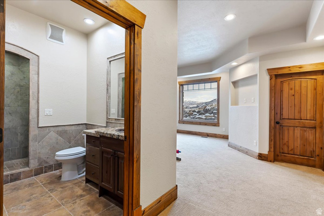 246 Woods Creek Road Morgan, UT 84050 - Photo 34 of 69 Recessed lighting, wood-finish trim, a bathroom with tiled flooring, a shower with tiled walls, and a vanity with a stone countertop