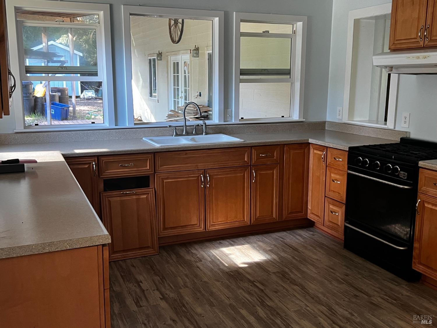 3761 East Blue Rock Road Garberville, CA 95542 - Photo 7 of 38 a kitchen with stainless steel appliances granite countertop a stove a sink and a microwave oven with wooden floor