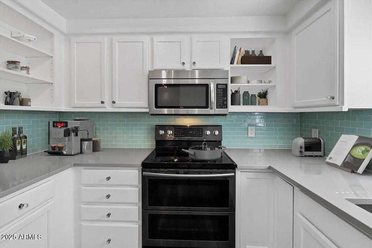 7575 East Indian Bend Road, Unit 2002 Scottsdale, AZ 85250 - Photo 3 of 24 a kitchen with white cabinets and black appliances