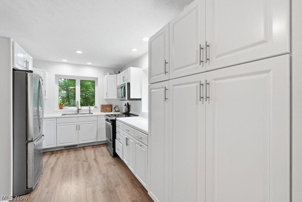 2323 Call Road Stow, OH 44224 - Photo 17 of 42 Kitchen featuring extensive white cabinetry, stainless steel appliances, wood-finish flooring, recessed lighting, and a window above the sink