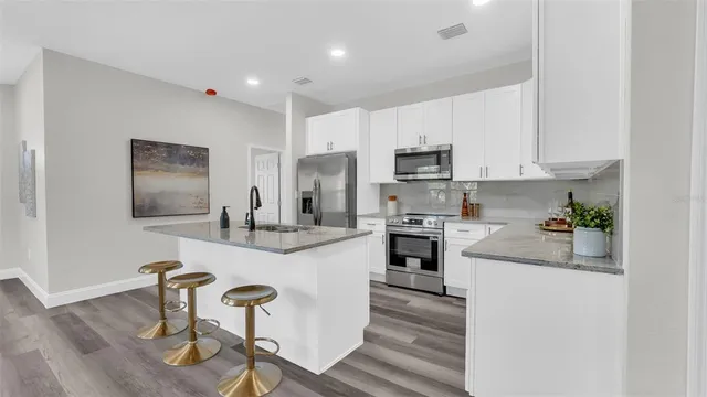 a kitchen with stainless steel appliances granite countertop a stove top oven a sink a counter space and cabinets