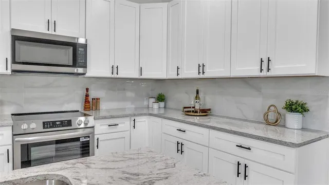 a kitchen with granite countertop white cabinets and stainless steel appliances
