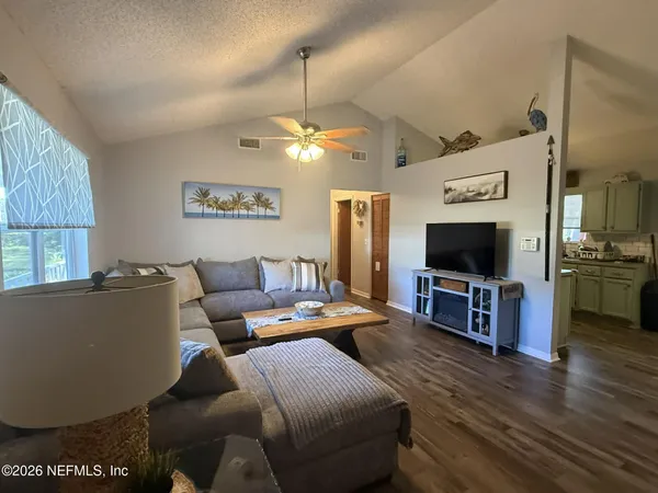 a living room with furniture a flat screen tv and kitchen view