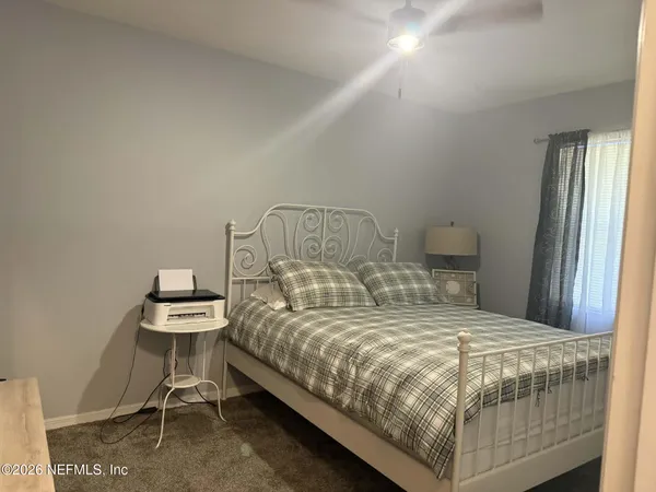 a bedroom with a bed a chair and a lamp on the table