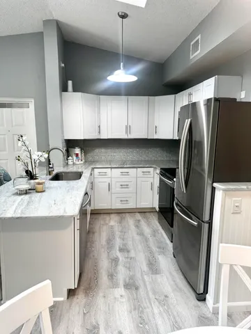 a kitchen with granite countertop a refrigerator a sink a stove a microwave and island