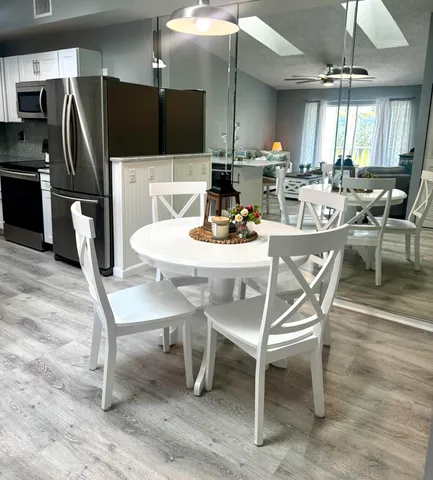 a dining room with stainless steel appliances kitchen island granite countertop a dining table chairs and a refrigerator