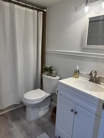 a bathroom with a sink a toilet a mirror and shower curtain