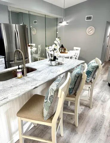 a kitchen with granite countertop a dining table chairs and a refrigerator