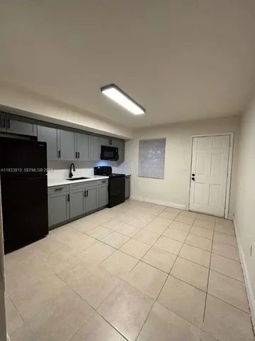 a large kitchen with a stove a refrigerator a sink and dishwasher with white cabinets