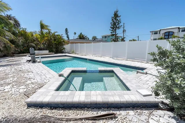 a view of swimming pool with a yard and palm trees